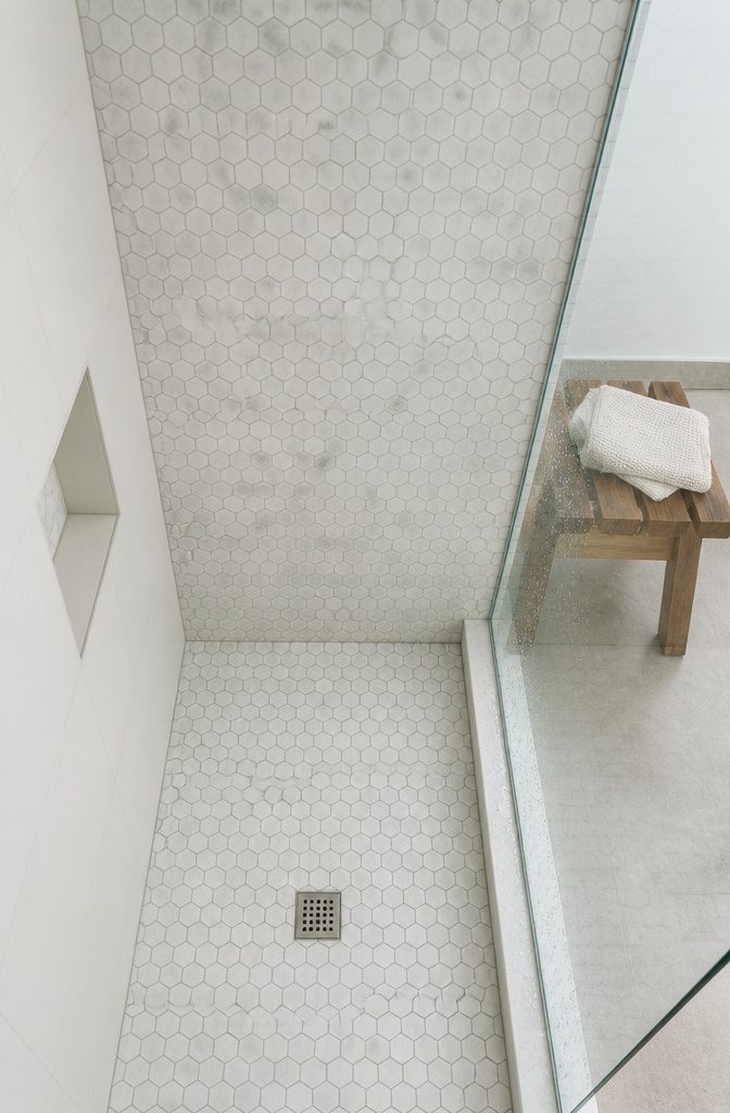 Marble-look hexagon mosaic tiles in a honeycomb pattern on a shower wall