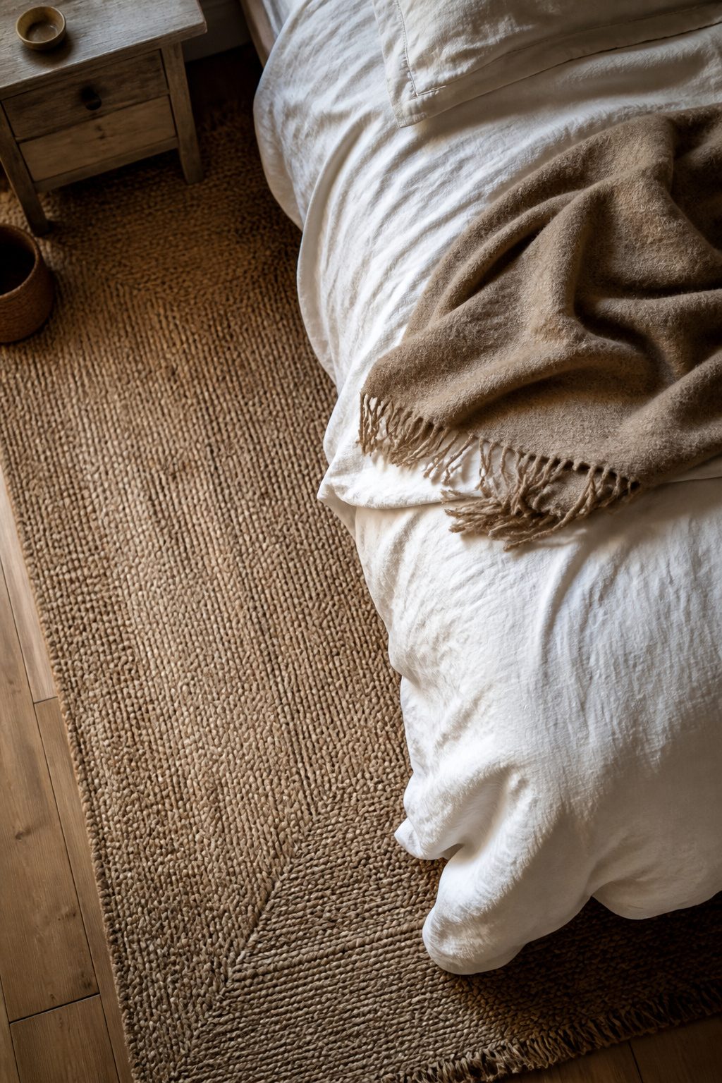 A jute rug layered with cotton bedding and a wool throw.