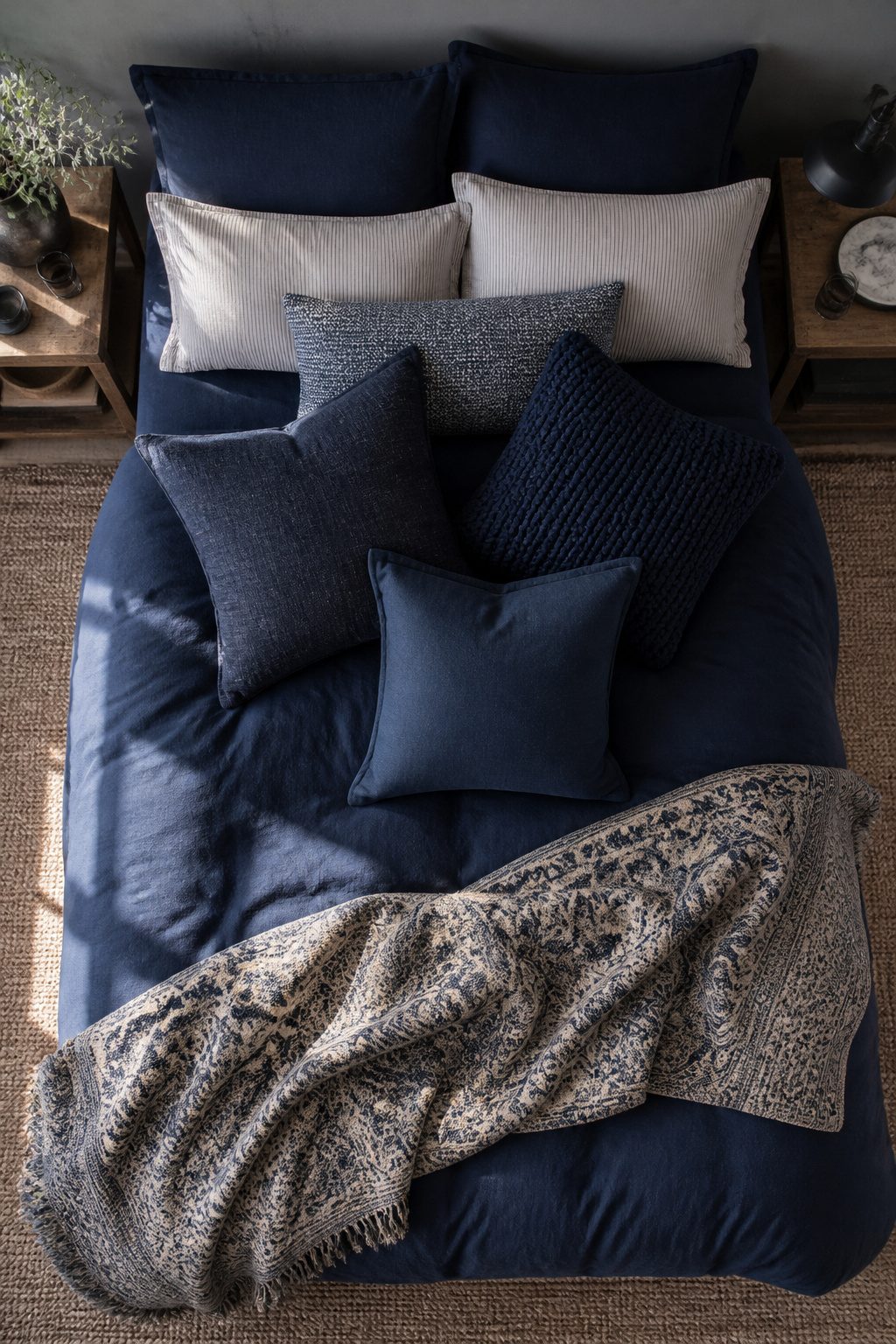 Three navy throw pillows on a bed with layered bedding.