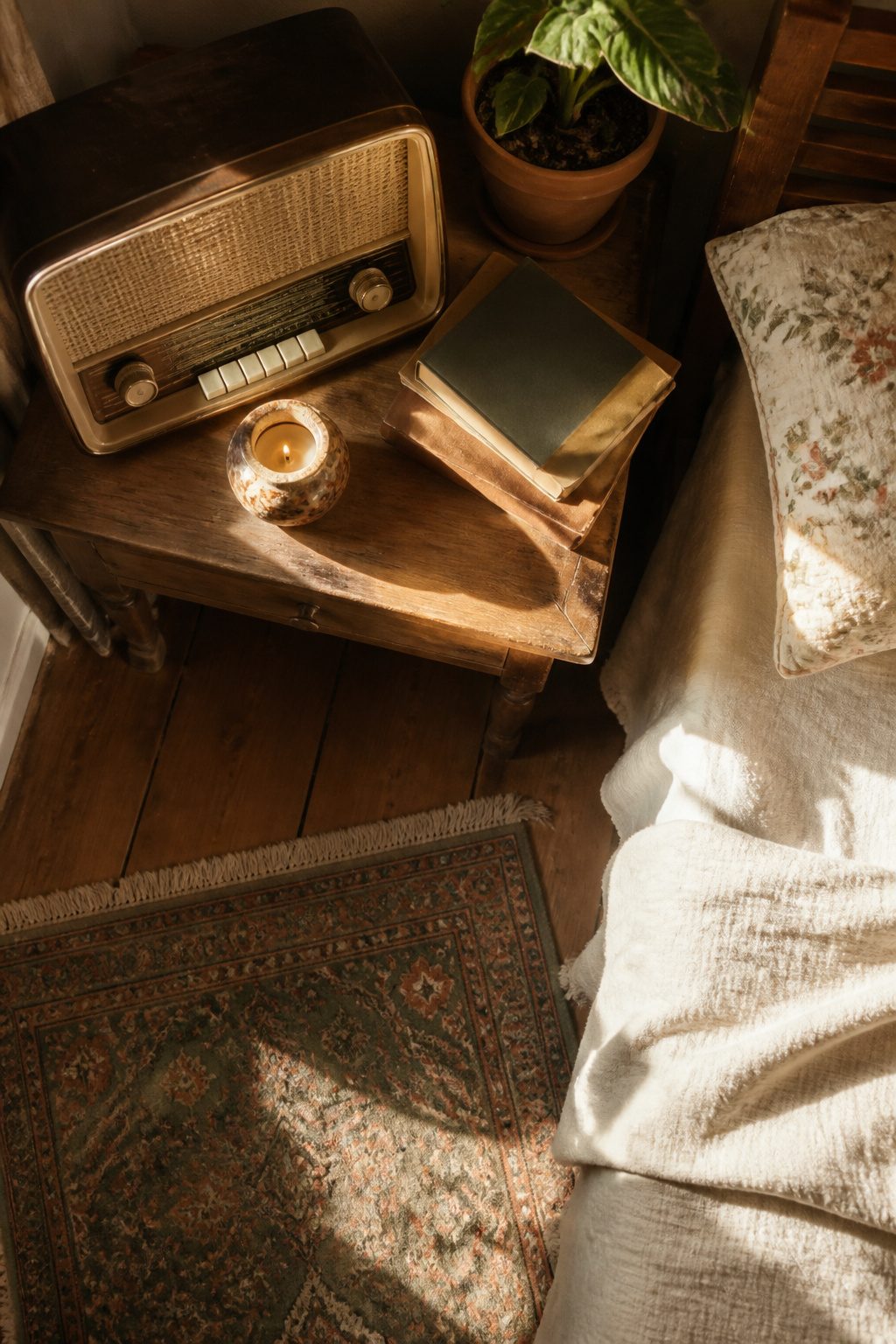 A vintage radio and a stack of old books on a nightstand.